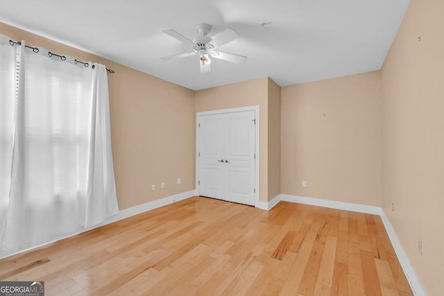 unfurnished bedroom with baseboards, a ceiling fan, a closet, and wood finished floors
