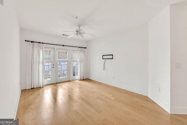 unfurnished room with light wood finished floors, baseboards, a ceiling fan, and visible vents