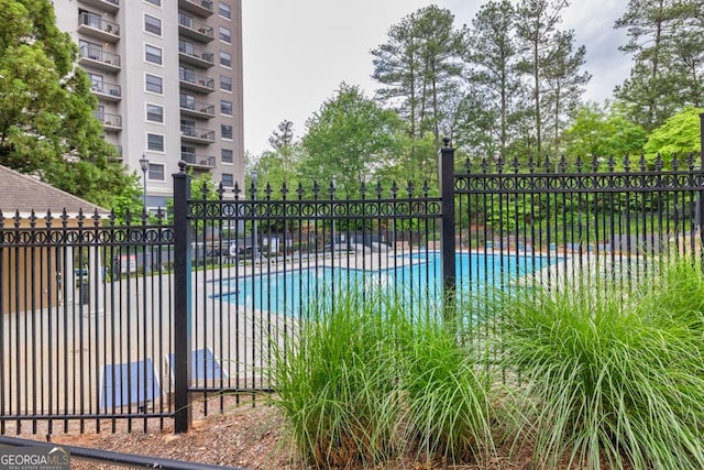 view of gate with fence and a community pool