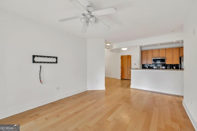 unfurnished living room featuring light wood finished floors, baseboards, and ceiling fan