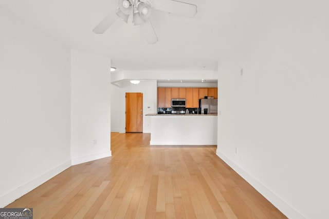 unfurnished living room featuring baseboards, light wood finished floors, and ceiling fan