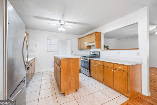 303 Jennys Cove Rd, Cleveland, GA 30528 - kitchen with a ceiling fan, under cabinet range hood, a kitchen island, light countertops, and appliances with stainless steel finishes