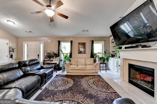 living area featuring ceiling fan, a premium fireplace, a textured ceiling, and carpet