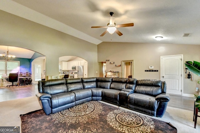 living area featuring vaulted ceiling, arched walkways, ceiling fan, a chandelier, and wood finished floors