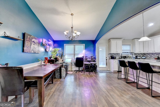 dining area with lofted ceiling, a chandelier, and wood finished floors