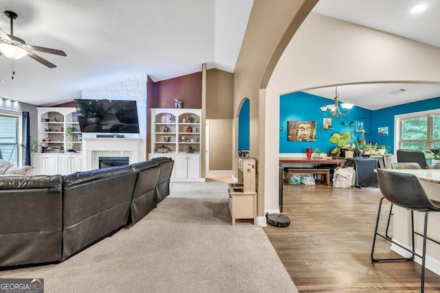 1553 Shoal Creek Dr, Winder, GA 30680 - living area with vaulted ceiling, a ceiling fan, a chandelier, a fireplace, and wood finished floors