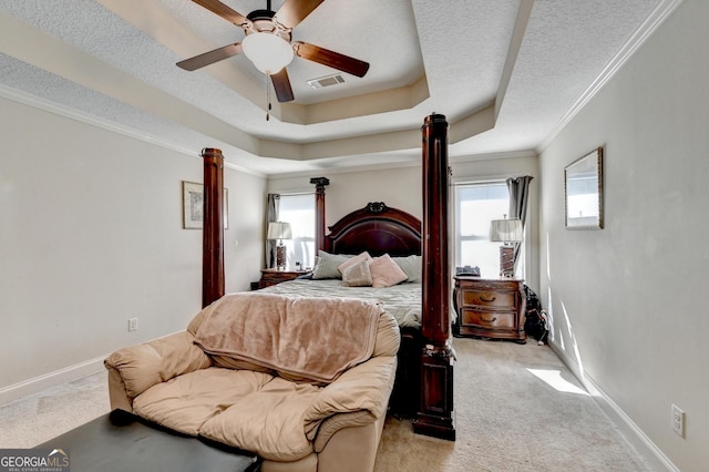 bedroom featuring light carpet, crown molding, baseboards, a tray ceiling, and a textured ceiling