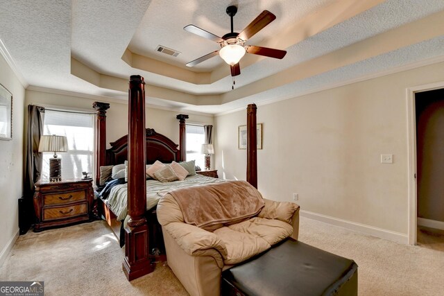 bedroom with light colored carpet, ornamental molding, baseboards, a tray ceiling, and a ceiling fan