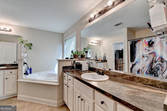 bathroom featuring a bath, two vanities, tile patterned floors, a textured ceiling, and a shower with shower curtain