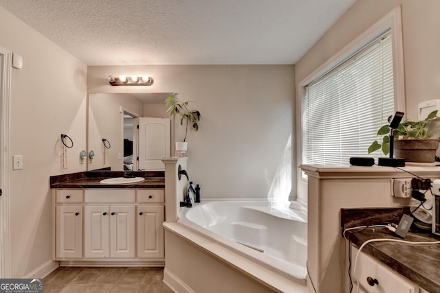 full bath featuring a bath, vanity, a textured ceiling, tile patterned flooring, and baseboards