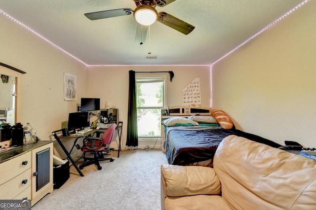 bedroom featuring light colored carpet, an office area, and ceiling fan