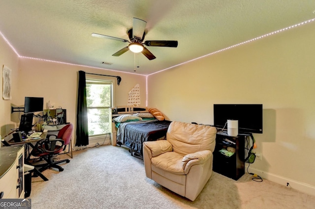 bedroom with an office area, carpet floors, baseboards, ceiling fan, and a textured ceiling