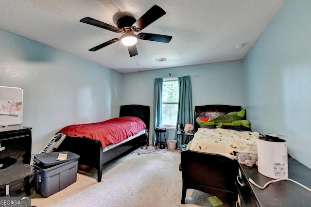 carpeted bedroom with ceiling fan and a textured ceiling