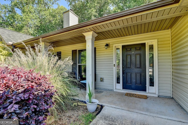 property entrance featuring a chimney and a porch