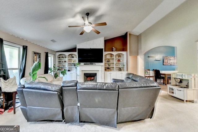 living area featuring lofted ceiling, ceiling fan, carpet flooring, and a fireplace