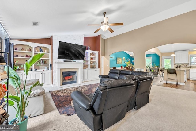 1553 Shoal Creek Dr, Winder, GA 30680 - living area with arched walkways, a ceiling fan, a fireplace, vaulted ceiling, and built in features