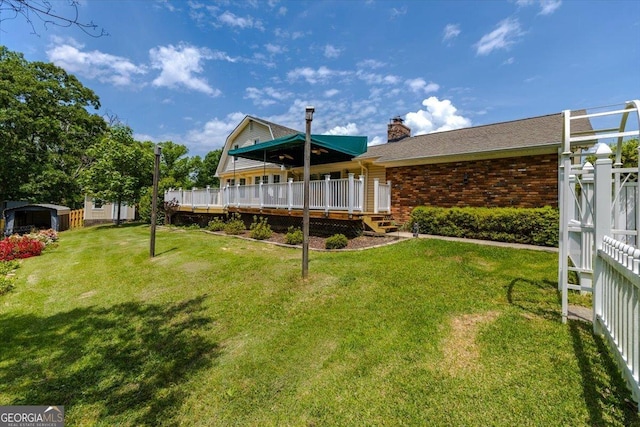 540 Commanche Dr, Macon, GA 31210 - back of house featuring brick siding, a deck, a chimney, and a lawn