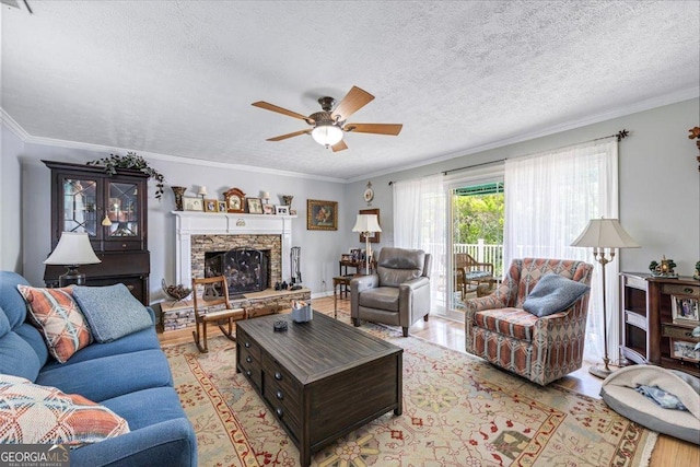 540 Commanche Dr, Macon, GA 31210 - living room with ornamental molding, a textured ceiling, a fireplace, a ceiling fan, and light wood-style floors