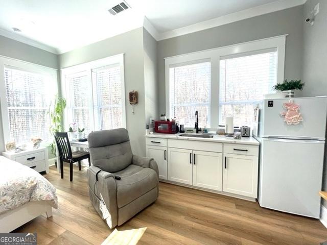 338 Grady St, Waleska, GA 30183 - bedroom featuring freestanding refrigerator, crown molding, multiple windows, and light wood-style floors