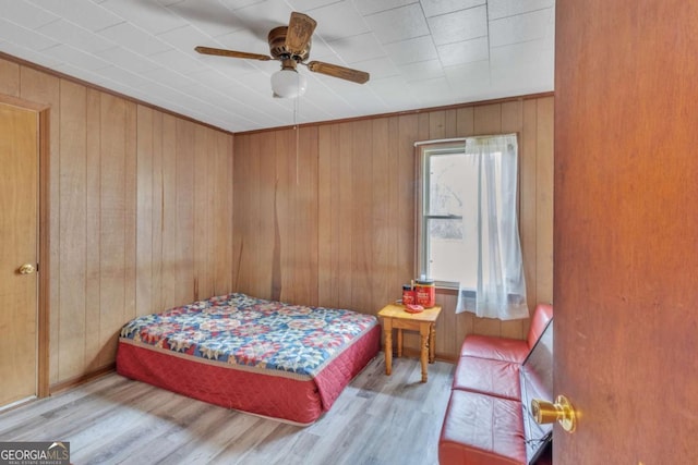 bedroom featuring wood walls, wood finished floors, and ceiling fan