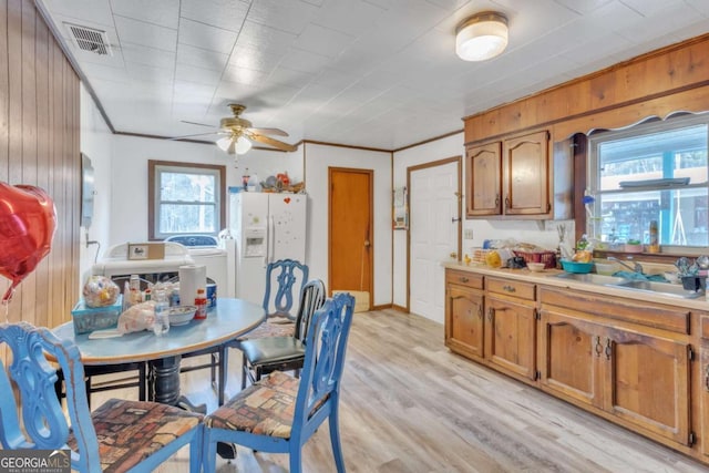 dining room featuring visible vents, ceiling fan, wooden walls, crown molding, and light wood-style floors