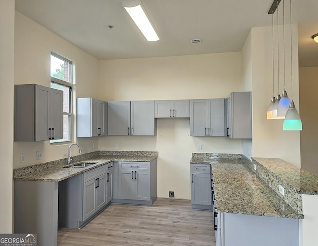 870 Mayson Turner Rd NW Unit 1447, Atlanta, GA 30314 - kitchen featuring light stone counters, a sink, gray cabinetry, and light wood finished floors