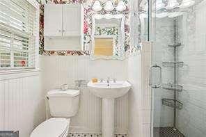 bathroom featuring a stall shower, toilet, and a sink