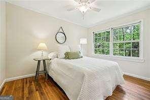 bedroom with baseboards, ornamental molding, wood finished floors, and a ceiling fan