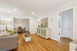 living area featuring ornamental molding, wood finished floors, baseboards, and recessed lighting