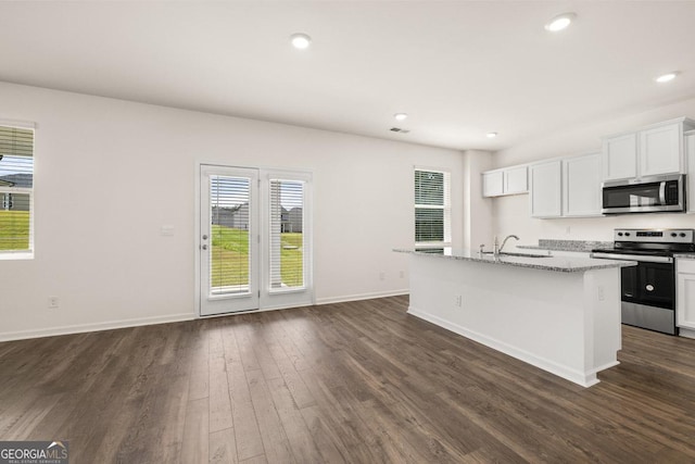 kitchen with an island with sink, stainless steel appliances, dark wood finished floors, baseboards, and recessed lighting
