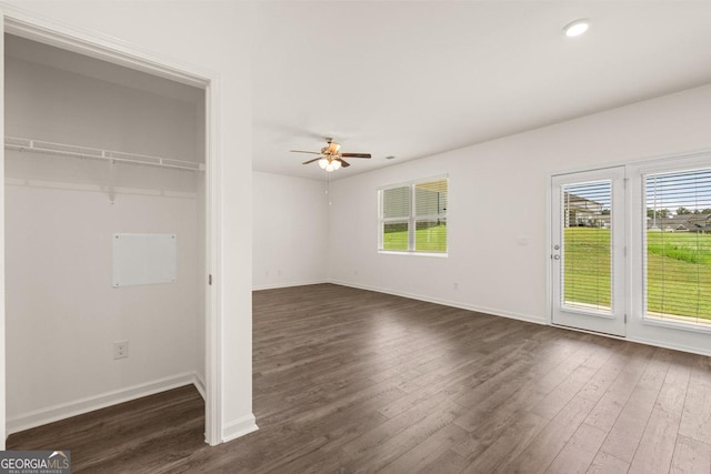 interior space featuring baseboards, multiple windows, and dark wood-type flooring