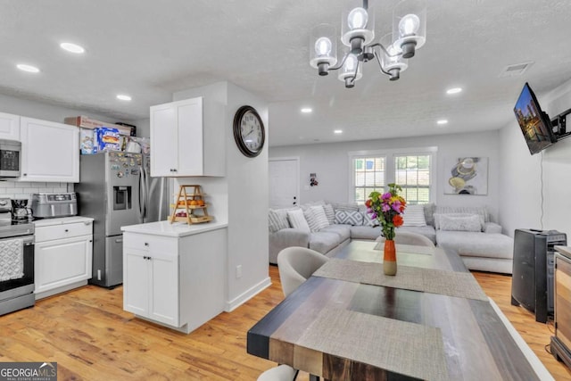 3819 Shane Ct, Ellenwood, GA 30294 - kitchen featuring white cabinetry, stainless steel appliances, open floor plan, and an inviting chandelier