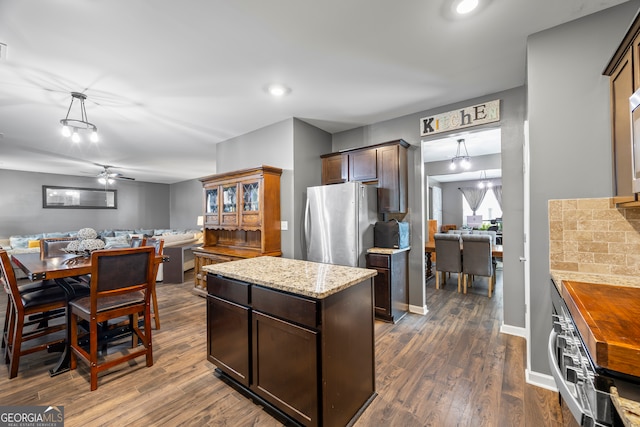 kitchen featuring freestanding refrigerator, dark brown cabinetry, dark wood-type flooring, and open floor plan