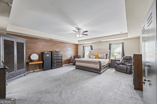 carpeted bedroom featuring wooden walls and a ceiling fan