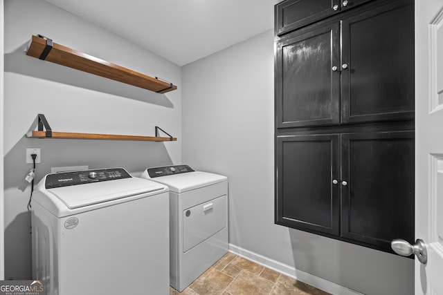 washroom featuring baseboards, cabinet space, washer and clothes dryer, and light stone finish floors