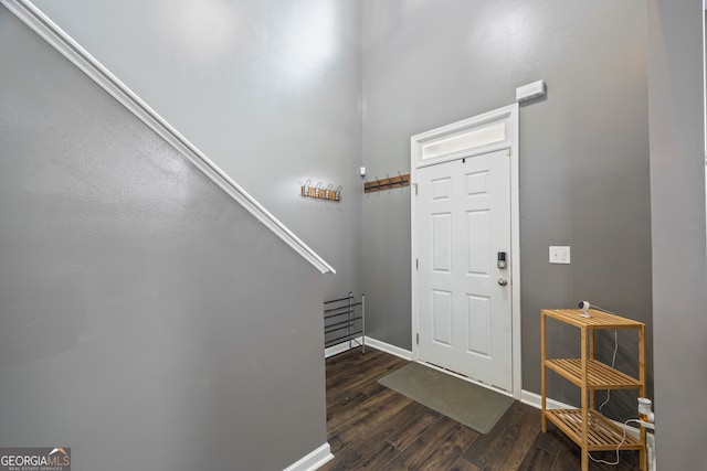 foyer featuring dark wood-type flooring, baseboards, and stairway