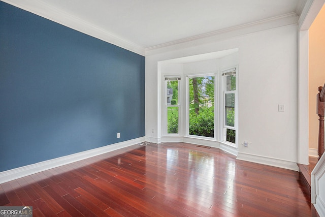 unfurnished room featuring crown molding, baseboards, and wood finished floors