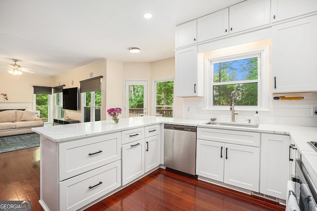 kitchen featuring stainless steel dishwasher, a peninsula, a sink, white cabinetry, and recessed lighting