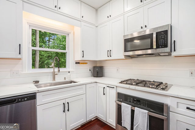 kitchen featuring appliances with stainless steel finishes, a sink, white cabinets, and dark wood-style floors