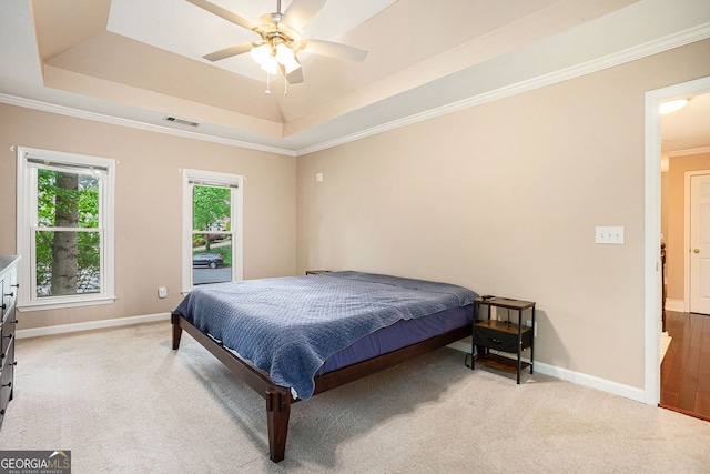 bedroom with a tray ceiling, light carpet, baseboards, crown molding, and ceiling fan
