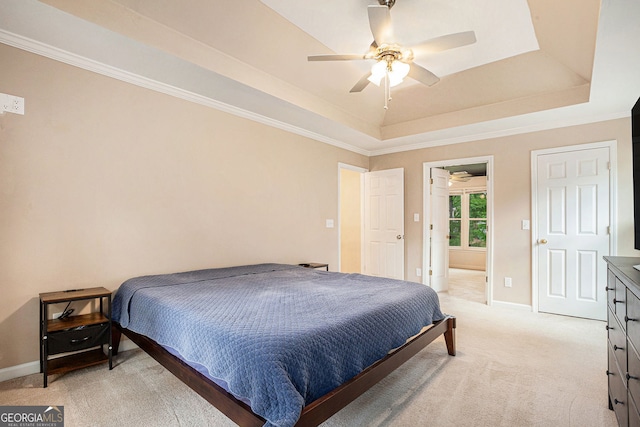 bedroom with a tray ceiling, light colored carpet, baseboards, crown molding, and connected bathroom