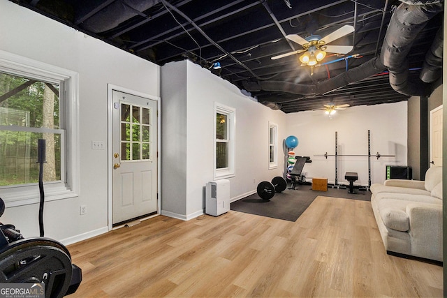 exercise area featuring a ceiling fan, wood finished floors, and baseboards