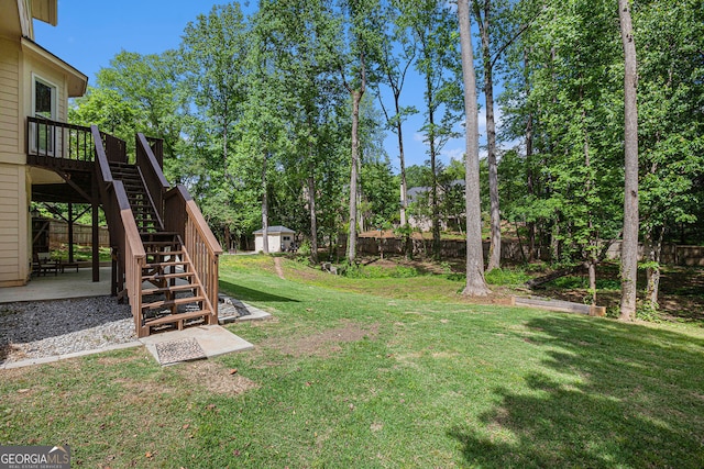 view of yard featuring stairway, a patio, a deck, view of wooded area, and an outbuilding