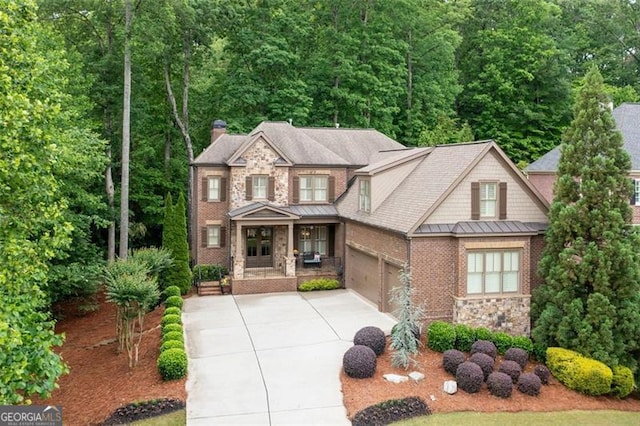 craftsman-style house featuring stone siding, an attached garage, a chimney, concrete driveway, and a standing seam roof