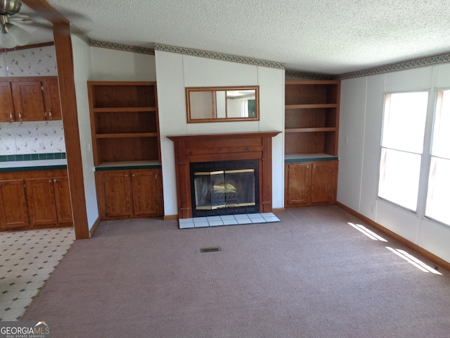 unfurnished living room featuring light carpet, visible vents, a fireplace with flush hearth, and a textured ceiling