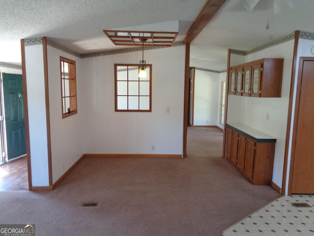 unfurnished room featuring light carpet, a textured ceiling, baseboards, and visible vents