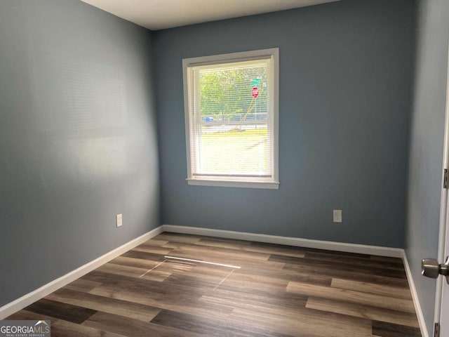 spare room featuring baseboards and wood finished floors