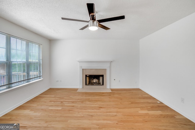3550 Willow Tree Trce, Decatur, GA 30034 - unfurnished living room with a ceiling fan, light wood-type flooring, a premium fireplace, a textured ceiling, and baseboards