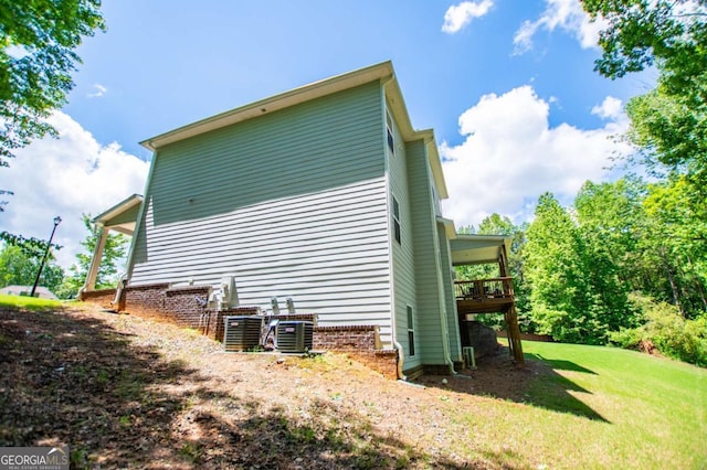view of side of property with a yard, a deck, and central AC unit