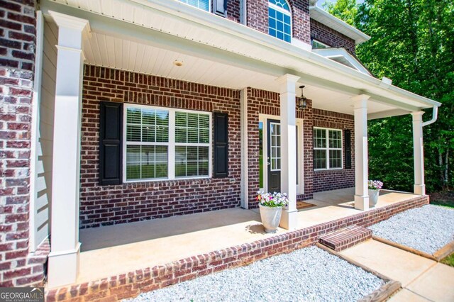 doorway to property featuring a porch and brick siding